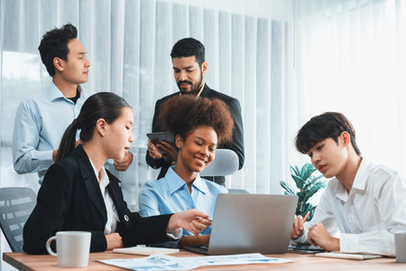 Happy diverse business people work together, discussing in corporate office. Professional and diversity teamwork discuss business plan on desk with laptop. Modern multicultural office worker. Concordの写真素材