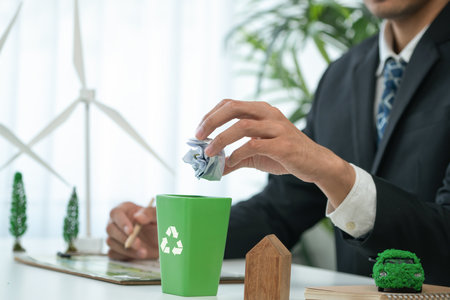 Businessman put paper waste on small tiny recycle bin in his office symbolize corporate effort on eco-friendly waste management by recycling for greener environment and zero pollution. Gyreの写真素材