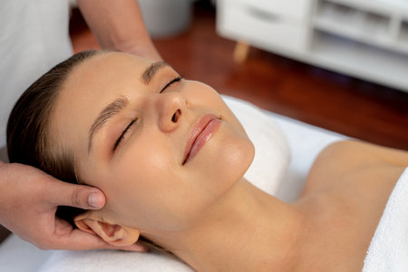 Caucasian woman enjoying relaxing anti-stress head massage and pampering facial beauty skin recreation leisure in dayspa modern light ambient at luxury resort or hotel spa salon. Quiescentの写真素材