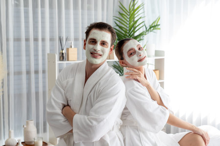 Blissful couple in bathrobe with facial cream mask enjoying serene ambiance of spa salon resort or...
