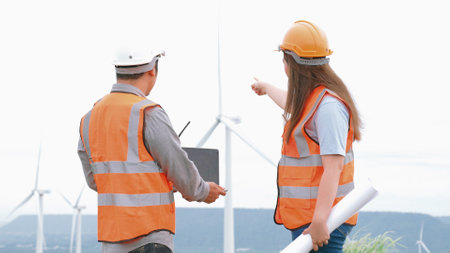 Male and female engineers working on a wind farm atop a hill or mountain in the rural. Progressive ideal for the future production of renewable, sustainable energy.の写真素材