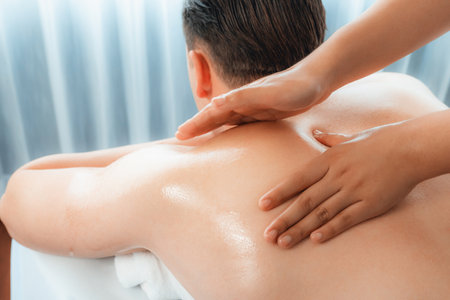 Caucasian man customer enjoying relaxing anti-stress spa massage and pampering with beauty skin recreation leisure in day light ambient salon spa at luxury resort or hotel. Quiescentの写真素材