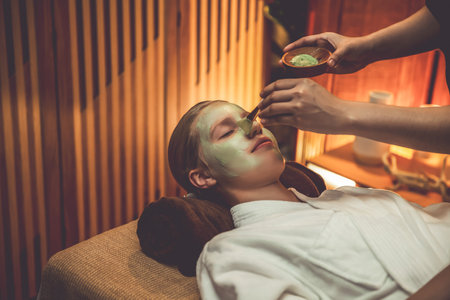 Serene ambiance of spa salon, woman customer indulges in rejuvenating with luxurious face cream massage with warm lighting candle. Facial skin treatment and beauty care concept. Quiescentの写真素材