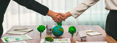 Business people shake hand over table with Eco concept mockup after made successful agreement deal on environmental conservation and sustainable energy matters to reduce CO2 emission. Trailblazingの写真素材