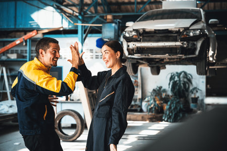 Two happy vehicle mechanic celebrate and high five after made successful car inspection or repair in automotive service car workshop. Technician team enjoy accomplishment together in garage. Oxusの写真素材