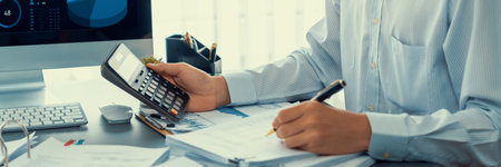 Corporate auditor calculating budget with calculator on his office desk. Dedicated accountant professional of accounting business company analyzing financial document to forecast income. Insightの写真素材