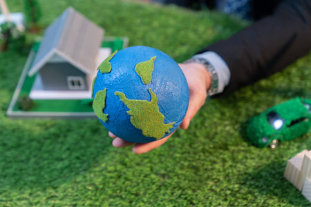 Eco business and save Earth concept shown by businessman or CEO holding paper globe in office with eco friendly mockup to promote CO2 and carbon footprint reduction for greener future. Quaintの写真素材