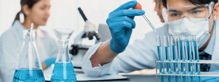 Group of dedicated scientist conduct chemical experiment in medical laboratory, carefully drop...