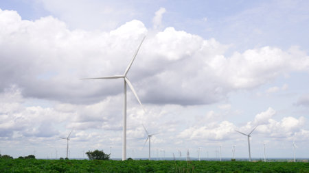 Progressive way of utilizing wind as renewable source of energy to power the modern way of life by wind turbine farm on green field or hill. Windmill generator generate electric with no CO2 emission.の写真素材