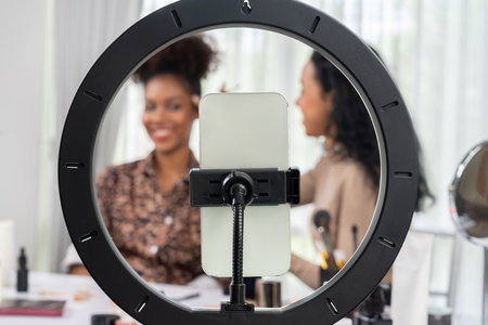Woman influencer shoot live streaming vlog video review makeup crucial social media or blog. Happy young girl with cosmetics studio lighting for marketing recording session broadcasting online.の写真素材