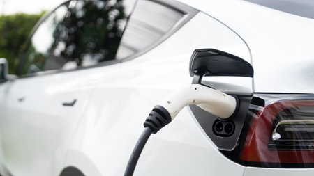 Closeup EV charger plug handle attached to electric vehicle port, recharging battery from charging station. Modern designed EV car and clean energy sustainability for better future concept. Synchronosの写真素材