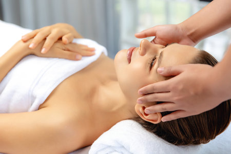 Caucasian woman enjoying relaxing anti-stress head massage and pampering facial beauty skin recreation leisure in dayspa modern light ambient at luxury resort or hotel spa salon. Quiescentの写真素材