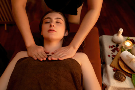 Top view woman customer enjoying relaxing anti-stress spa massage and pampering with beauty skin recreation leisure in warm candle lighting ambient salon spa at luxury resort or hotel. Quiescentの写真素材