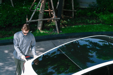 Young man travel with EV electric car charging in green sustainable city outdoor garden in summer shows urban sustainability lifestyle by green clean rechargeable energy of electric vehicle innardsの写真素材