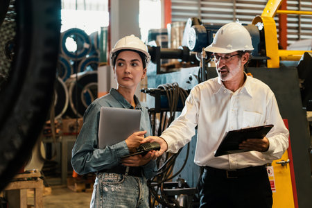 Factory engineer manager with assistant using laptop to conduct inspection of steel industrial...