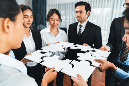 Multiethnic business people holding jigsaw pieces and merge them together as effective solution solving teamwork, shared vision and common goal combining diverse talent. Meticulousの写真素材