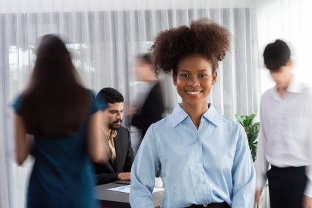 Young African businesswoman portrait poses confidently with diverse coworkers in busy meeting room...