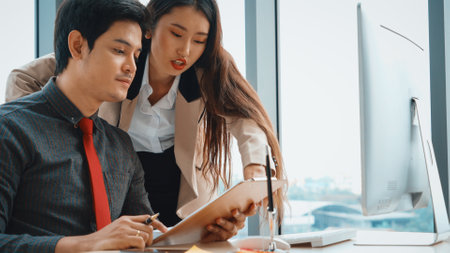 Two business people talk project strategy at office meeting room. Businessman discuss project planning with colleague at modern workplace while having conversation and advice on financial report. Jivyの写真素材