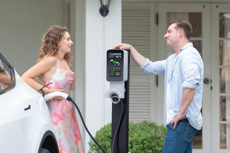 Happy and lovely couple with eco-friendly conscious recharging electric vehicle from EV home...
