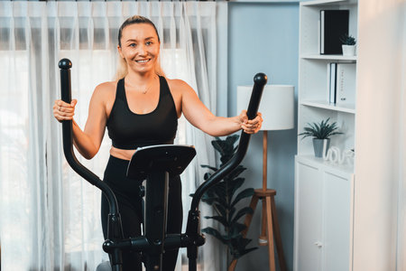 Active senior woman running on elliptical running machine at home portrait as fitness healthy...