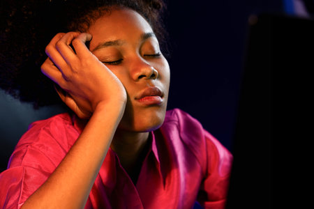 Exhausted and sleepy young African businesswoman taking a nap in her arm on desk at home office....