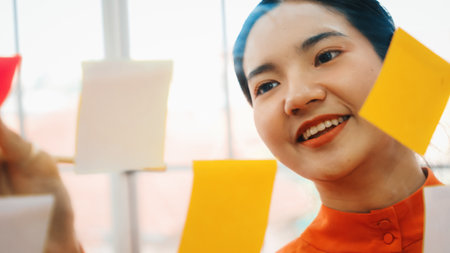 Business people work on project planning board in office and having conversation with coworker friend to analyze project development . They use sticky notes posted on glass to make it organized. Jivyの写真素材