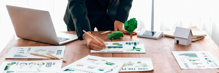Businessman planning for green business strategy in office with paper documents focused on...