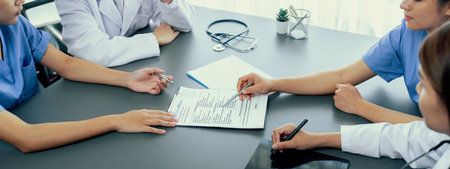 Doctor and nurse in medical meeting discussing strategic medical treatment plan together with report...