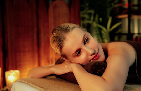 Caucasian woman customer enjoying relaxing anti-stress spa massage and pampering with beauty skin recreation leisure in warm candle lighting ambient salon spa at luxury resort or hotel. Quiescentの写真素材