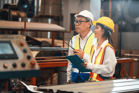 Factory foreman worker and engineer conduct inspection of industrial steel machine and metal material quality product. Manufacturing facility with machinery safety and quality control. Exemplifyingの写真素材