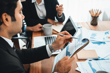 Diverse group of business analyst team analyzing financial data report paper on office table. Chart and graph dashboard by business intelligence analysis for strategic marketing planning Habilimentの写真素材