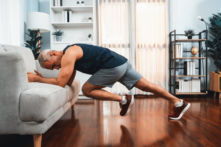 Active and fit senior man warmup and stretching using furniture before home exercising routine at living room. Healthy fitness lifestyle concept after retirement for pensioner. Cloutの写真素材