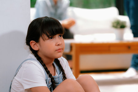 Stressed and unhappy young girl huddle in corner crying and sad while her parent arguing in...