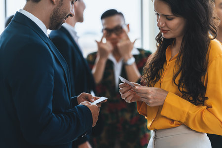 Successful businesswoman holding the name card during talking to manager about their cooperation. Cropped image of exchanging name card between businessman and businesswoman. Side view. Intellectual.の写真素材