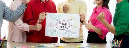 A cropped image of successful businesspeople presents new product marketing strategy using a mind map. Young creative business team brainstorm marketing idea together at modern office. Variegated.の写真素材