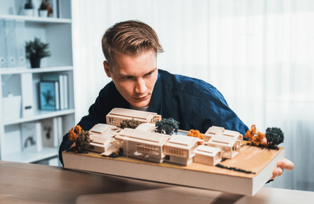 Architect designer studies elegant house model, reviewing structure design for improvement with construction plan on table. Creativity and innovation in architectural design. Iterationの写真素材