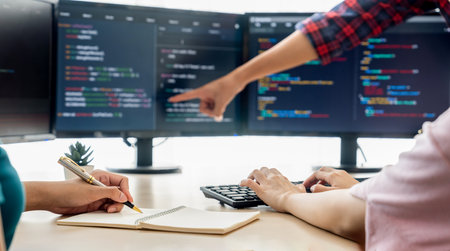 Female programer taking a note while young skilled web developer present program while computer...