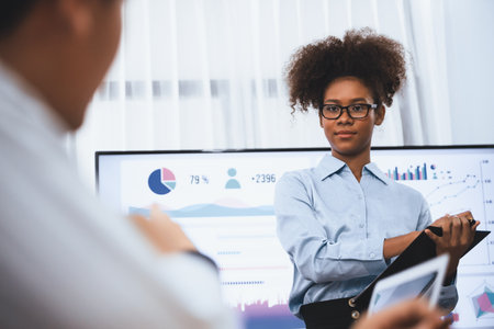 Young african businesswoman presenting data analysis dashboard on TV screen in modern meeting. Business presentation with group of business people in conference room. Concordの写真素材