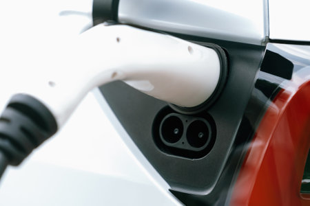 Closeup EV charger plug handle attached to electric vehicle port, recharging battery from charging...