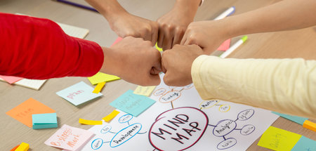 Young happy creative startup group join circle fist bump hands together surrounded by marketing...