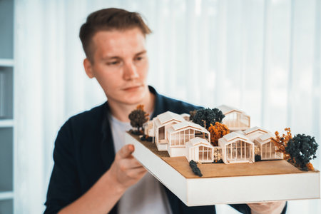 Architect designer studies elegant while holding house model, reviewing structure design for improvement with construction plan on table. Creativity and innovation in architectural design. Iterationの写真素材