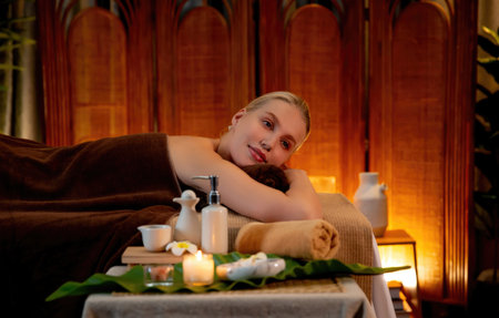 Caucasian woman customer enjoying relaxing anti-stress spa massage and pampering with beauty skin recreation leisure in warm candle lighting ambient salon spa at luxury resort or hotel. Quiescentの写真素材