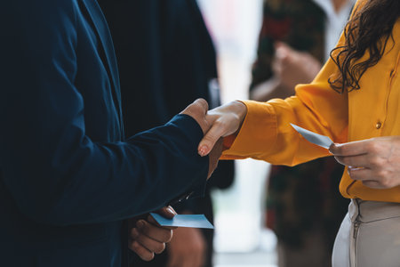 Businessmen shaking hand and making a contract in the sign of agreement, cooperation with businesswoman. Cropped image of managers holding business cards. Their partners standing behind. Intellectual.の写真素材