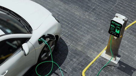 Aerial view electric car recharging battery from EV charging station at city center public car park....