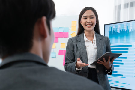 Young asian businesswoman presenting data analysis dashboard on TV screen in modern meeting. Business presentation with group of business people in conference room. Concordの写真素材