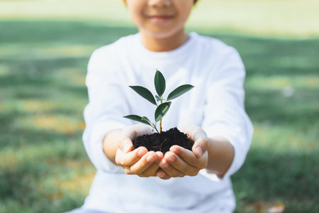 Promoting eco awareness on reforestation and long-term environmental sustainability with asian boy holding sprout. Nurturing greener nature for future generation with sustainable ecosystem. Gyreの写真素材