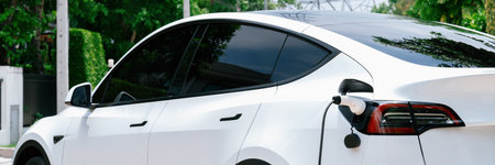 EV electric car recharge battery at parking lot in green city park. Alternative clean energy technology for rechargeable automobile for sustainable and eco friendly urban travel. Panorama Expedientの写真素材