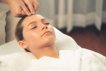 Caucasian woman enjoying relaxing anti-stress head massage and pampering facial beauty skin recreation leisure in dayspa modern light ambient at luxury resort or hotel spa salon. Quiescentの写真素材
