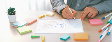 Skilled businessman brainstorms marketing ideas using mind maps. Successful male startup leader...