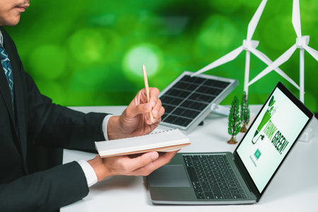 Businessman working in office developing plan or project on eco-friendly alternative energy with solar cell technology display on computer screen for greener environment as apart of CSR effort. Gyreの写真素材